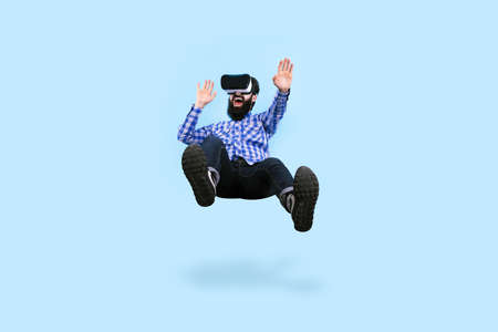 cheerful bearded man in glasses virtual reality levitating on blue backgroundの写真素材