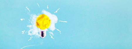 crumpled yellow paper light bulb on a blue background with smoke, concept idea, panoramic mock-up with space for textの写真素材