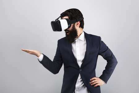 surprised businessman in VR glasses looking on empty hand, virtual reality concept, mock-up image