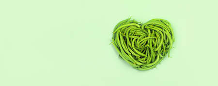 Heart of green beans on green background,  top view.の写真素材