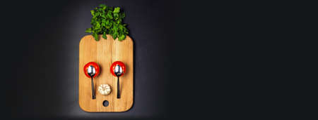 cartoon funny surprised face of tomatoes, spoons, garlic and parsley lined on the kitchen wooden board, with space for text, the concept of creative and fun cooking, flat lay imageの写真素材