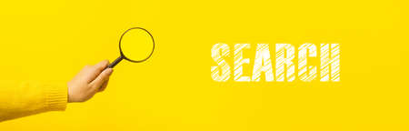 magnifier in hand  over yellow background, panoramic image with inscription search