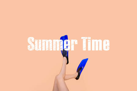 female sexy legs in flippers over peach background, concept of summer timeの写真素材