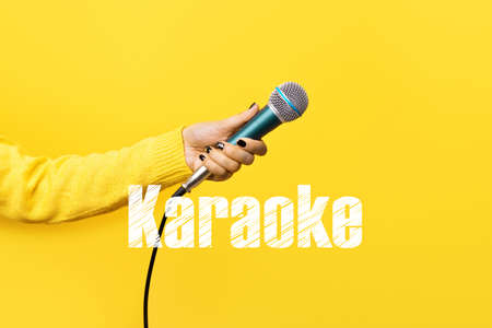 hand holding microphone over yellow background, karaoke conceptの写真素材