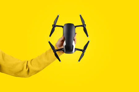 drone in hand over yellow background, shooting device concept