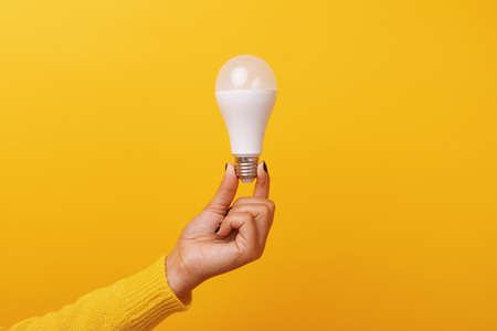 light bulb in hand over yellow background
