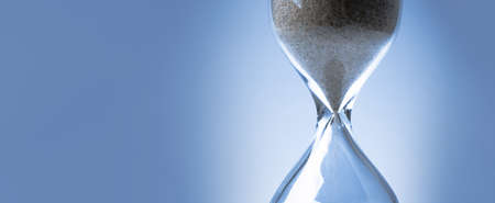 Sand flowing through an hourglass concept for time running out, background