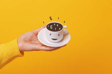 hand holding coffee cup over yellow background
