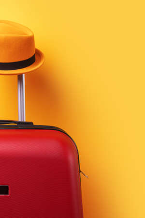 Suitcase with hat over yellow background minimal creative travel conceptの写真素材