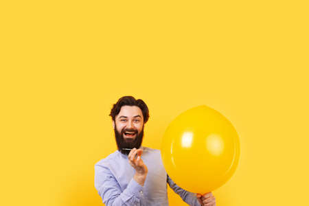 Man holding needle over yellow air balloon, a moment before bubble burst.の写真素材