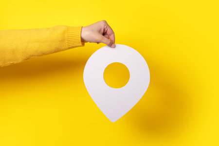 white map pointer 3d pin. Location symbol in hand over yellow backgroundの写真素材