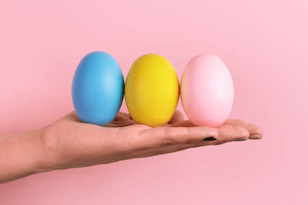 easter eggs on hand over pink background, happy easter concept