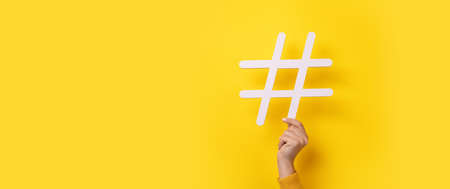 hand showing HASHTAG over yellow background, business concept, panoramic mock-upの写真素材