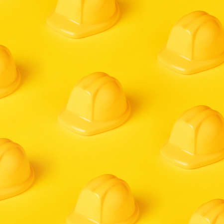 toy helmet pattern over yellow background, protection hat for constructionの写真素材