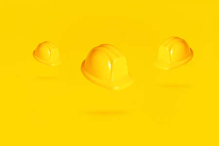 levitating hardhats over yellow background, helmets in air over yellow backgroundの写真素材