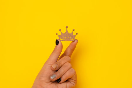 wooden crown in hand over yellow background, concept for king, queen power.の写真素材