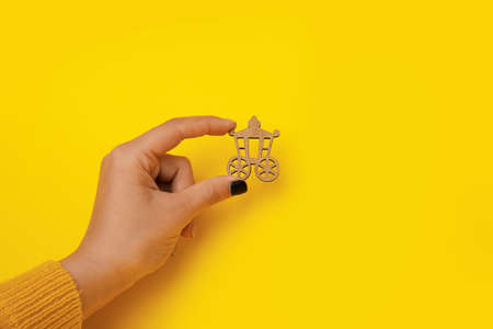 wooden carriage in hand over yellow background, vintage transport
