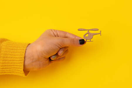 wooden helicopter in hand over yellow backgroundの写真素材