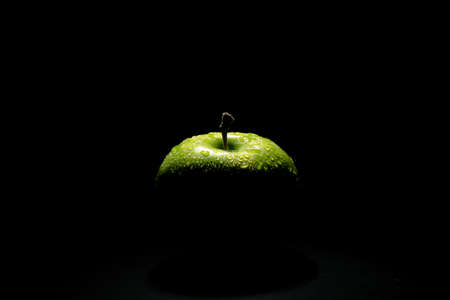 Perfect fresh green apple with water drop over black backgroundの写真素材