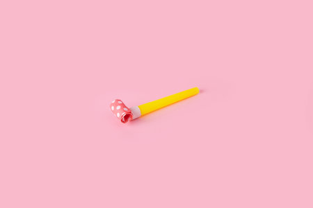 Rolled festive noisemaker or party whistle horn over pink backgroundの写真素材
