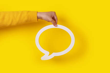Dialogue bubble in hand over yellow background