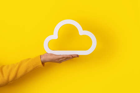 hand holding cloud icon over yellow backgroundの写真素材
