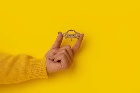 wooden UFO in hand over yellow backgroundの写真素材