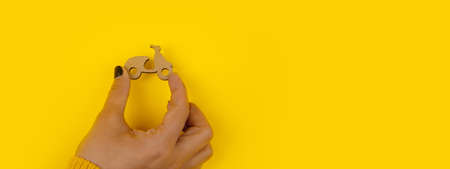 wooden scooter in hand over yellow background, fast delivery concept, panoramic mock-upの写真素材