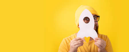 man holding rocket over yellow background, concept of successful startup, panoramic layoutの写真素材