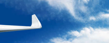 Wing of airplane over blue sky, panoramic layout