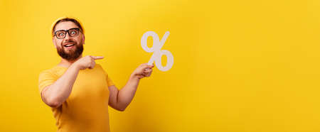 smiling man showing percentage sign over yellow background, panoramic layoutの写真素材