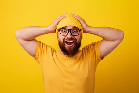 surprised man wearing glasses over yellow background, wow emotionの写真素材