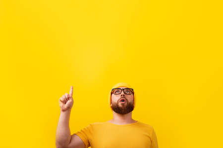 surprised bearded man with finger up, looking up over yellow background, advertising conceptの写真素材
