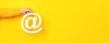 email sign in hand over yellow background, panoramic layoutの写真素材