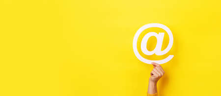 email sign in hand over yellow background, panoramic layout