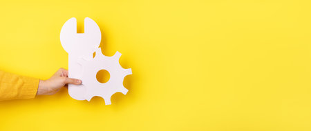 Service tools symbol in hand over yellow background, concept of repair, panoramic layoutの写真素材