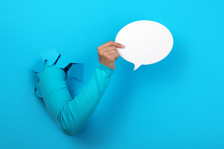 Talk bubble speech icon in hand over blue backgroundの写真素材