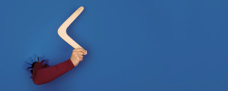 hand holding boomerang over blue background, panoramic layoutの写真素材