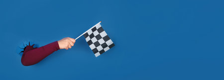 hand holding checkered flag over blue background, panoramic layoutの写真素材