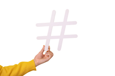 hand holding big white hash sign, hashtag symbol of internet trends and popular blogs, recommendation to follow social media content isolated on white backgroundの写真素材
