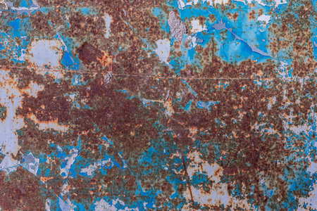 Close-up of a corroded metal surface with blue peeling paint and heavy rust for a grungy industrial...