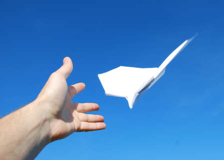 paper aeroplane in hands on the skyの写真素材