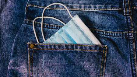 Medical face mask and money in jeans back pocket background. Concept for the new normal or new...