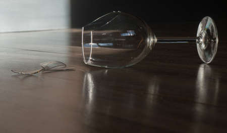 Broken wine glass goblet on the wooden floorの写真素材