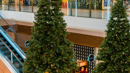 Festive gold decorations with baubles, stars and twinkling lights on an interior shopping mall Christmas tree in a close up view with copy space for your seasonal greetingの写真素材