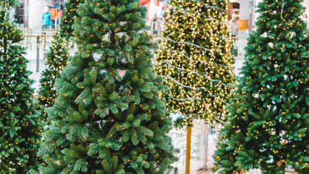 Festive gold decorations with baubles, stars and twinkling lights on an interior shopping mall Christmas tree in a close up view with copy space for your seasonal greetingの写真素材