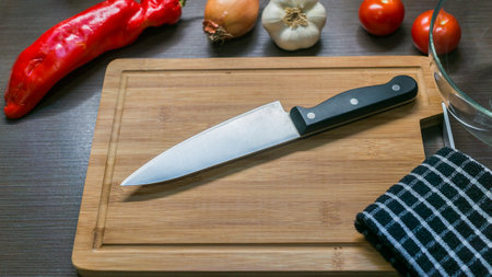big kitchen Knife on cutting board with vegetablesの写真素材