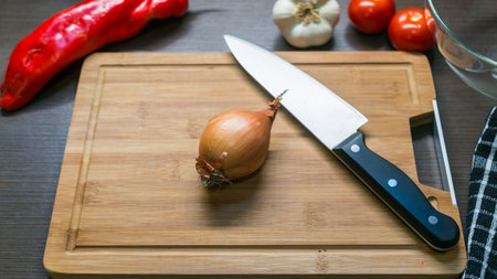 Top view of fresh yellow onion and vegetables on cutting board, kitchen backgroundの写真素材