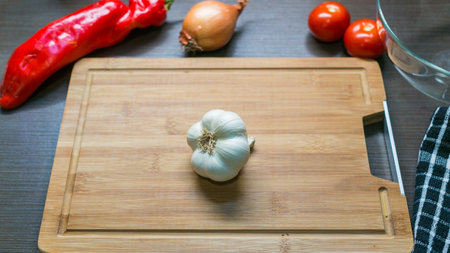 Top view of fresh white garlic and vegetables on cutting board, kitchen backgroundの写真素材