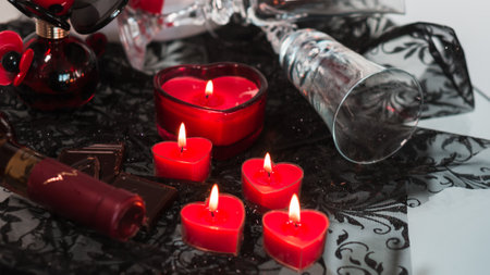 Valentine's Day Romantic Dinner. Date. Table setting with Champagne in two glasses, candles and gift box over holiday red background with heartsの写真素材